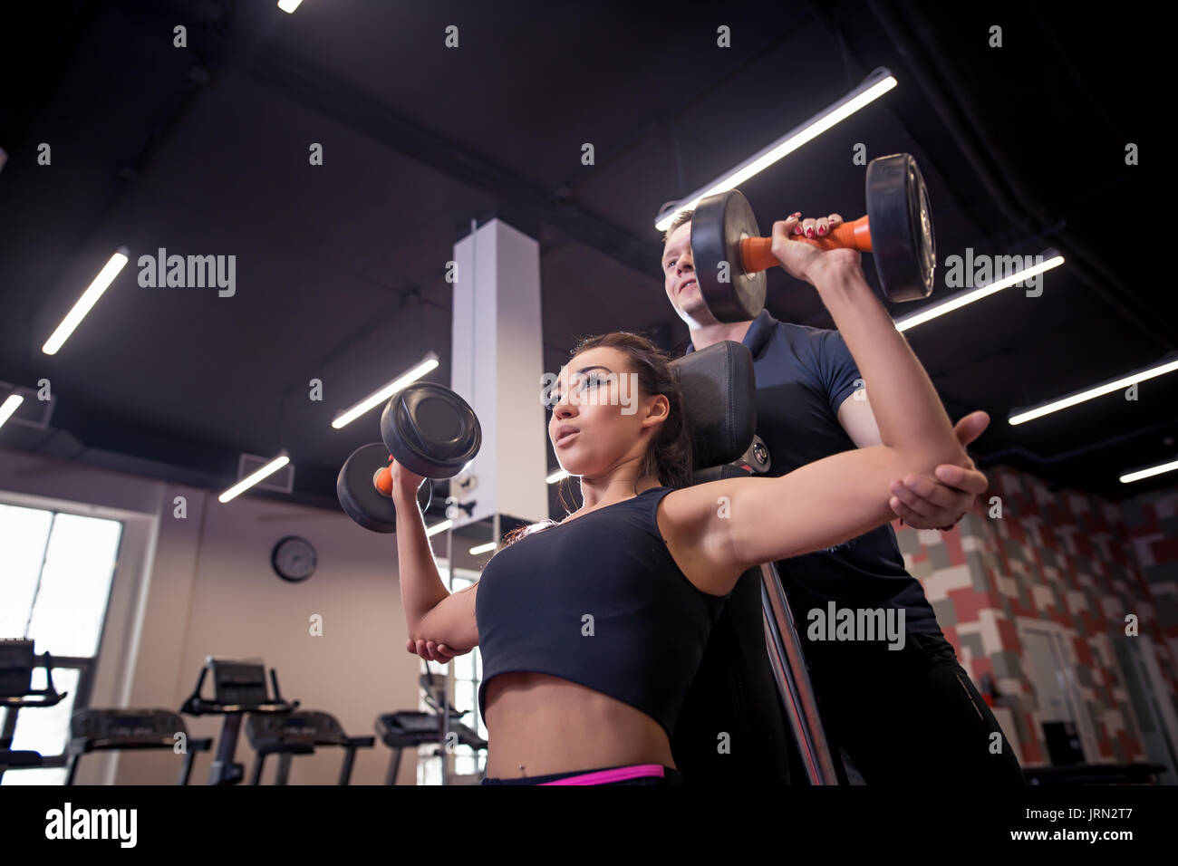 gym woman personal trainer man with weight training equipment Stock