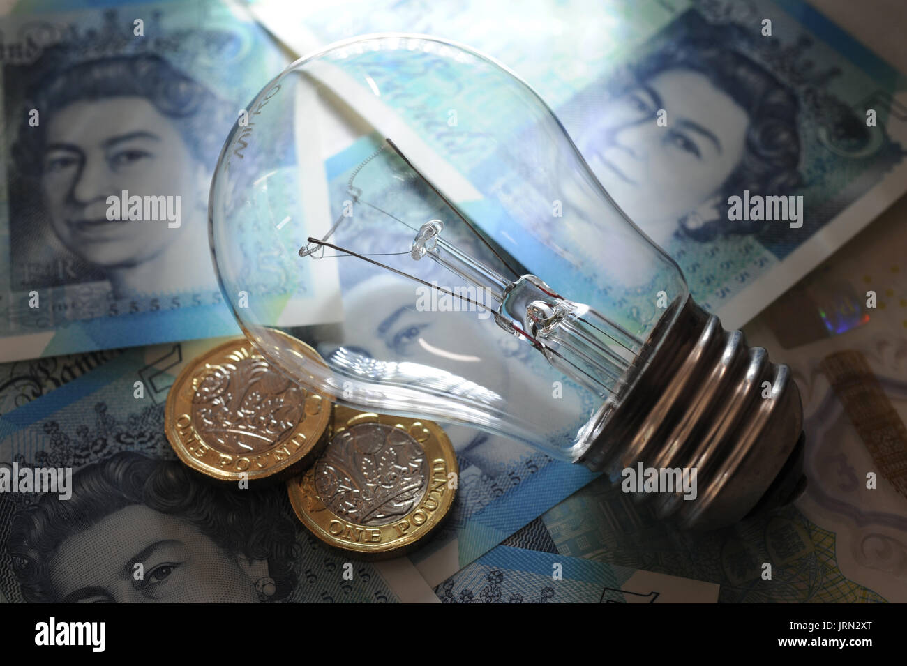 ELECTRIC LIGHT BULB WITH BRITISH MONEY RE ENERGY PRICES ELECTRICITY SUPPLIERS RISING FUEL COSTS HOUSEHOLD BUDGETS UK Stock Photo