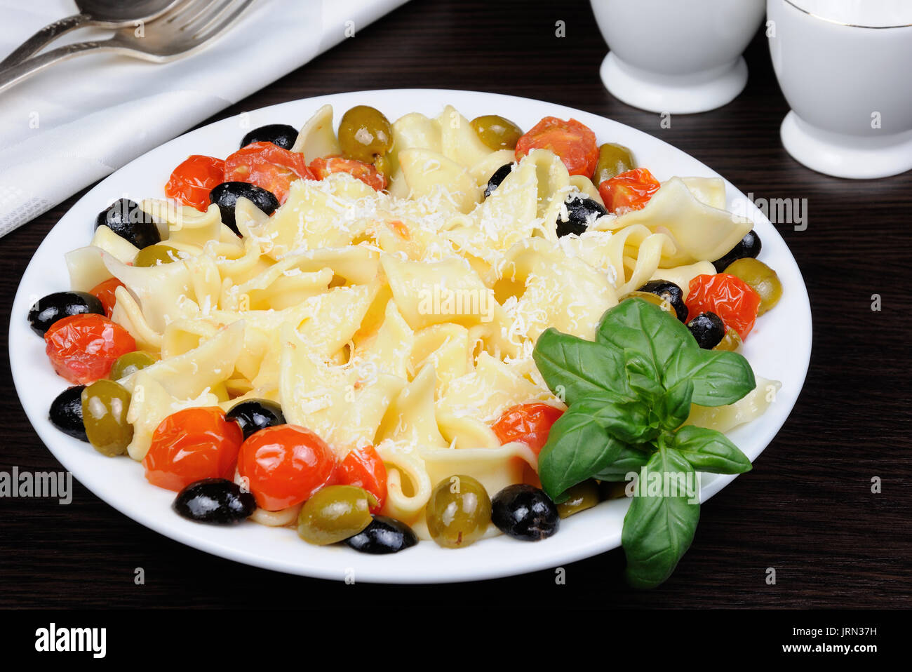 Pasta with olive, garlic, basil and tomatoes and seasoned with Parmesan cheese. Stock Photo