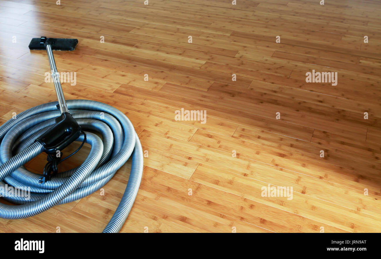 Beautiful bamboo hardwood floor with a central vacuum cleaner Stock