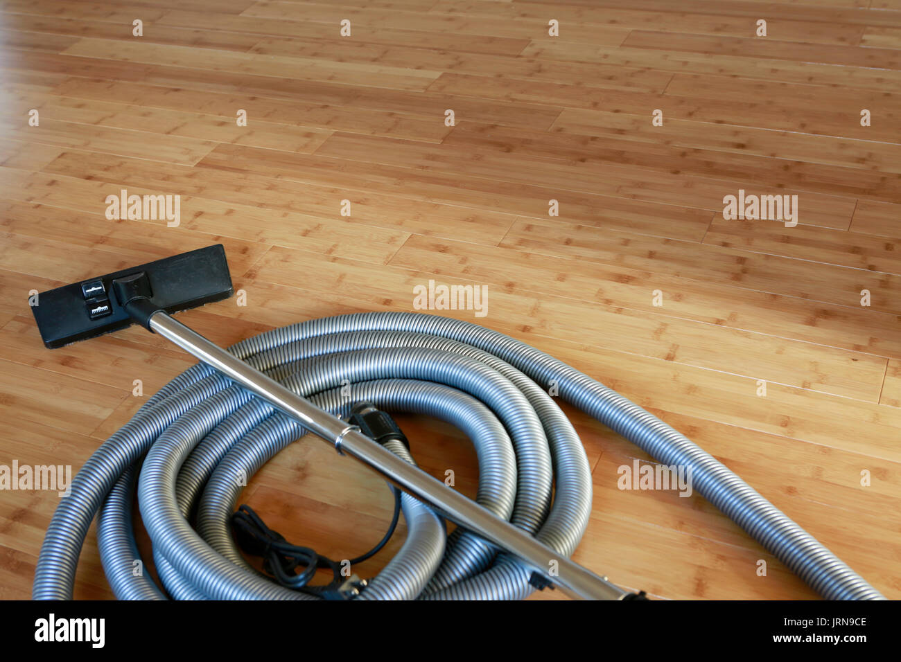 Beautiful bamboo hardwood floor with a central vacuum cleaner Stock