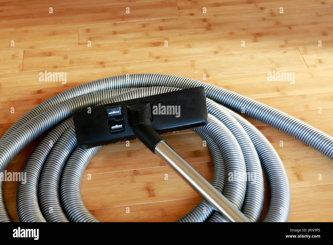 Beautiful bamboo hardwood floor with a central vacuum cleaner Stock