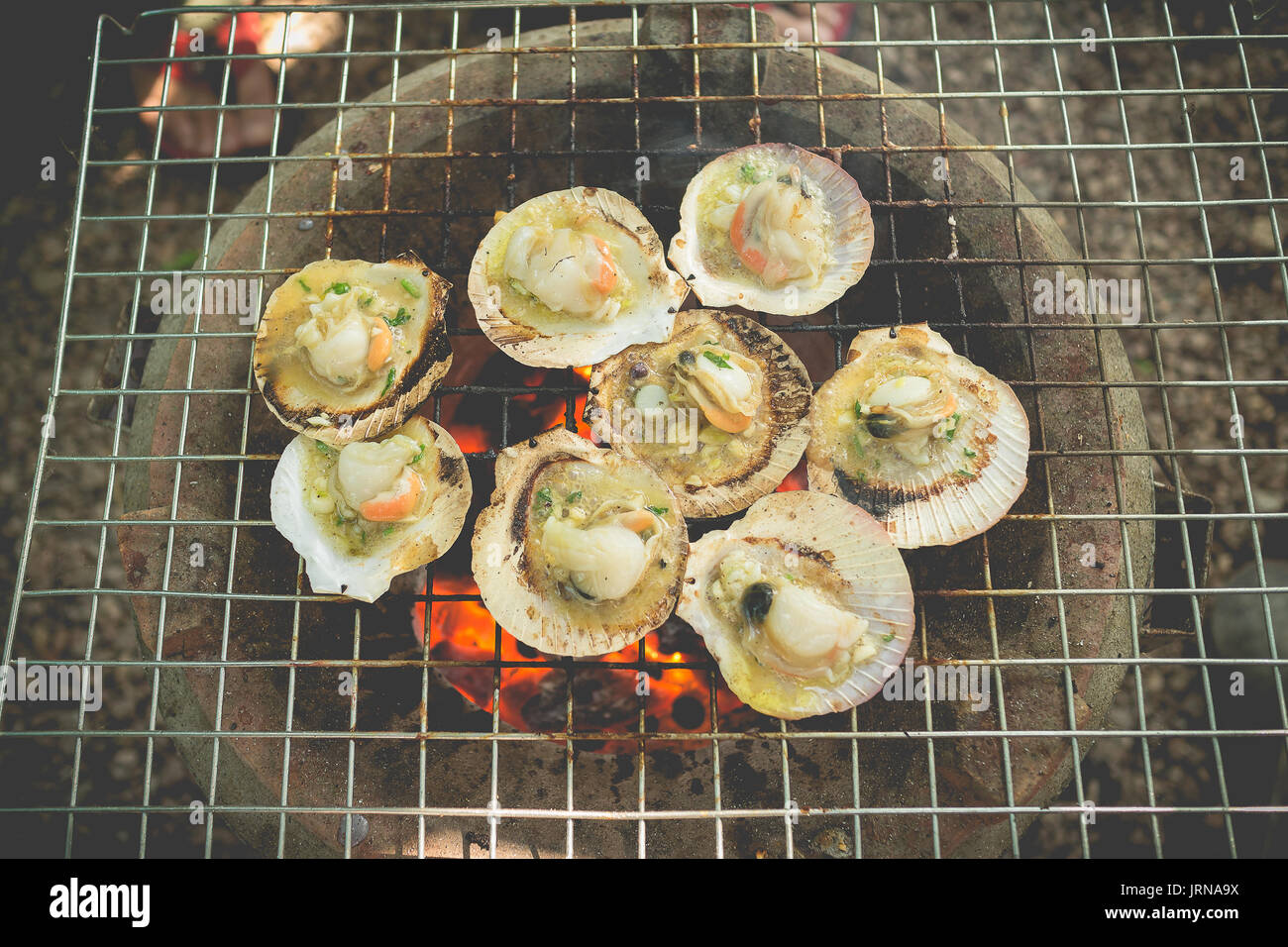 Grilled fresh scallops with butter and herb on flaming grill Stock