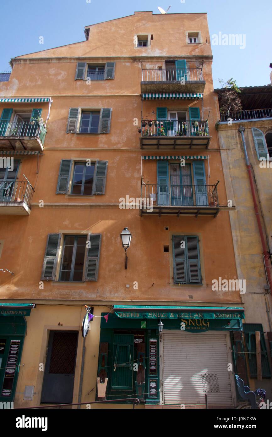 Shop front below traditional apartment exterior with window shutters and balconies, Nice, France Stock Photo
