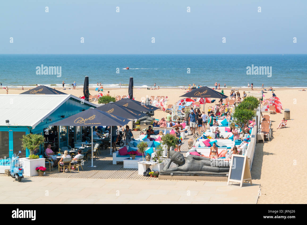 People enjoying and relaxing on lounge terrace of waterfront beach club in Scheveningen, The Hague, Netherlands Stock Photo