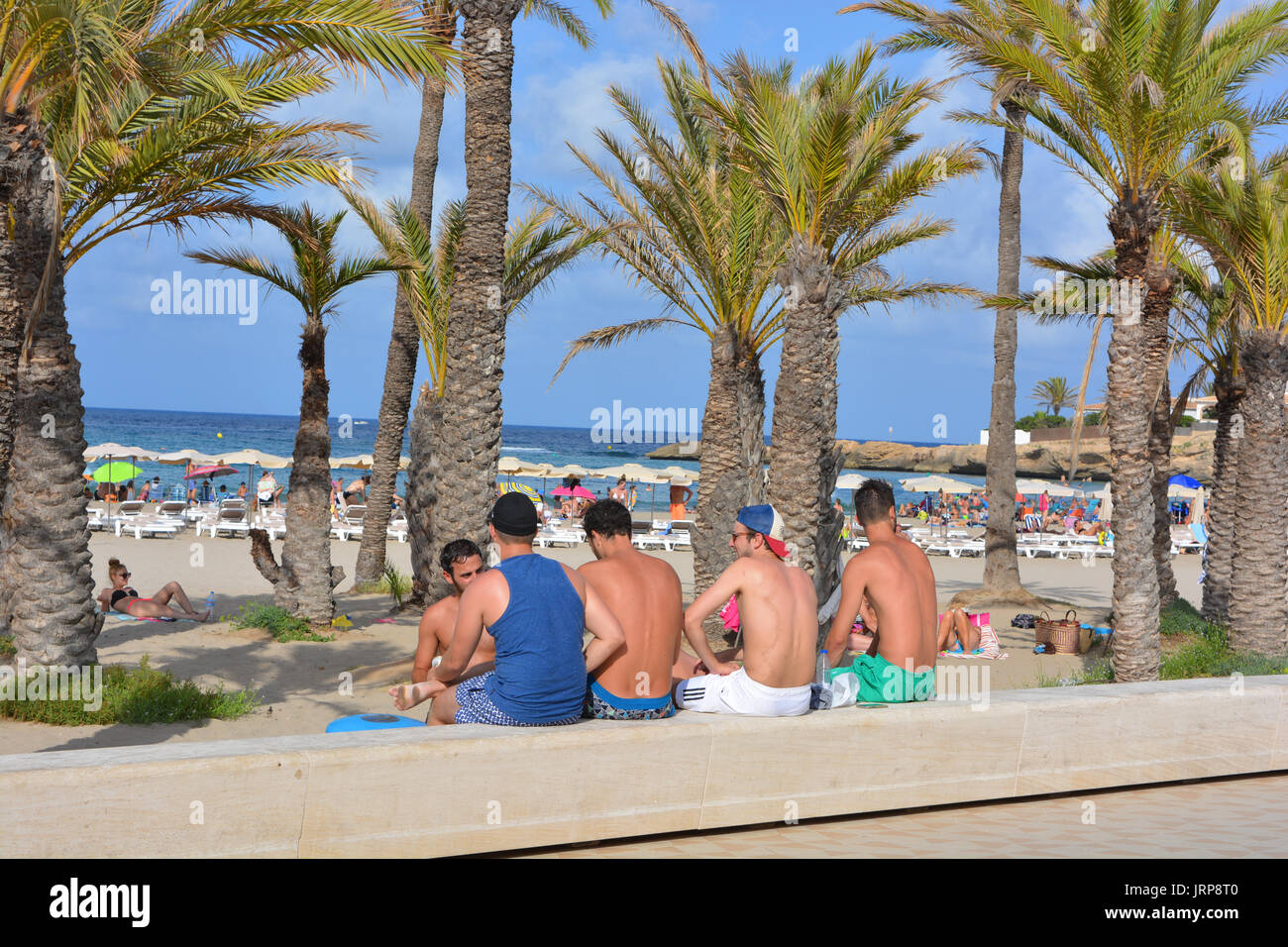 Group of men sitting on the wall at the Arenal Beach, Javea, Stock Photo