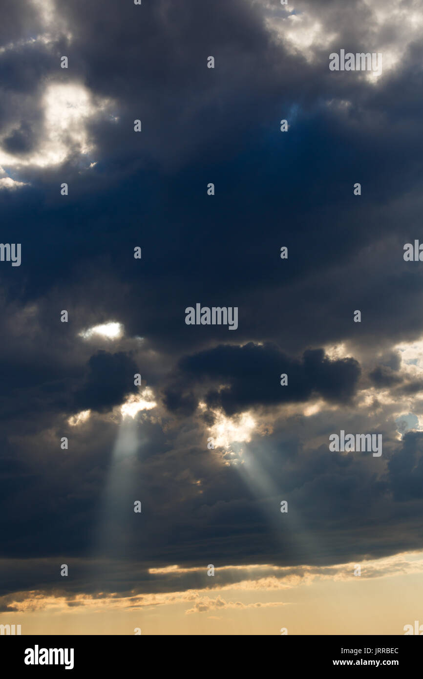 Rays of sunlight beaming through gray clouds Stock Photo