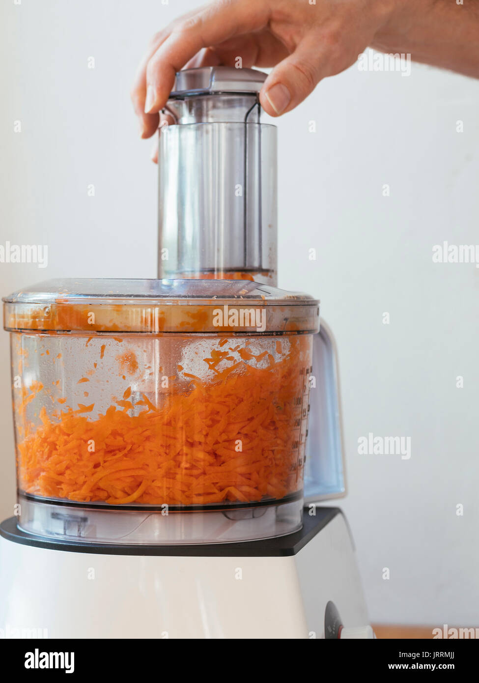 Man grating a carrot in a food processor Stock Photo