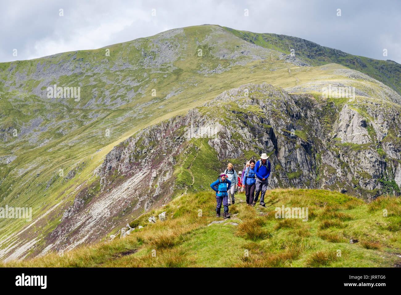 Hikers hiking up Pen yr Helgi Du with Carnedd Llewelyn behind in Carneddau mountains of Snowdonia National Park. Ogwen, Conwy, North Wales, UK Stock Photo