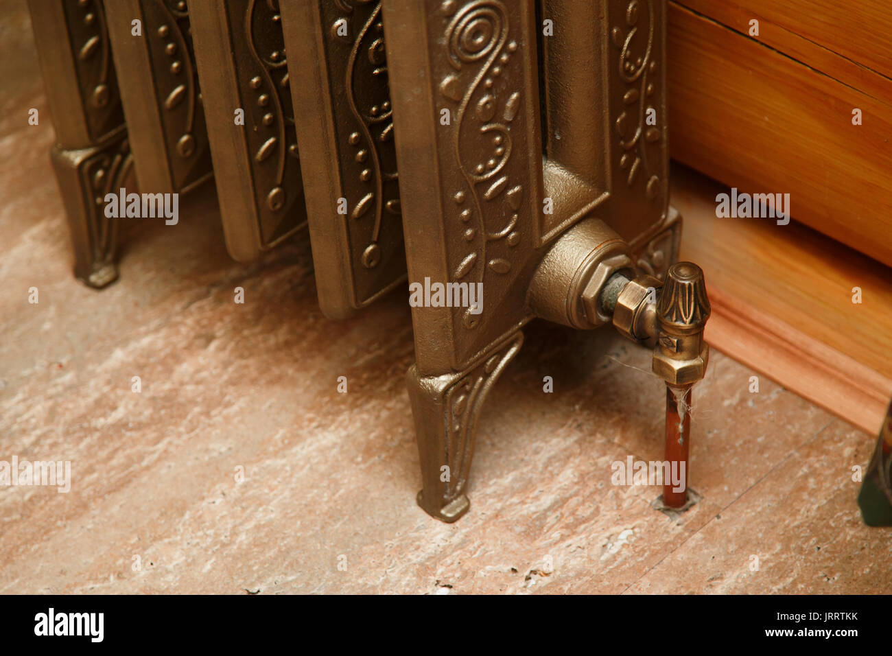 Retro styled cast iron radiator with valve and copper pipe. Close up Stock Photo