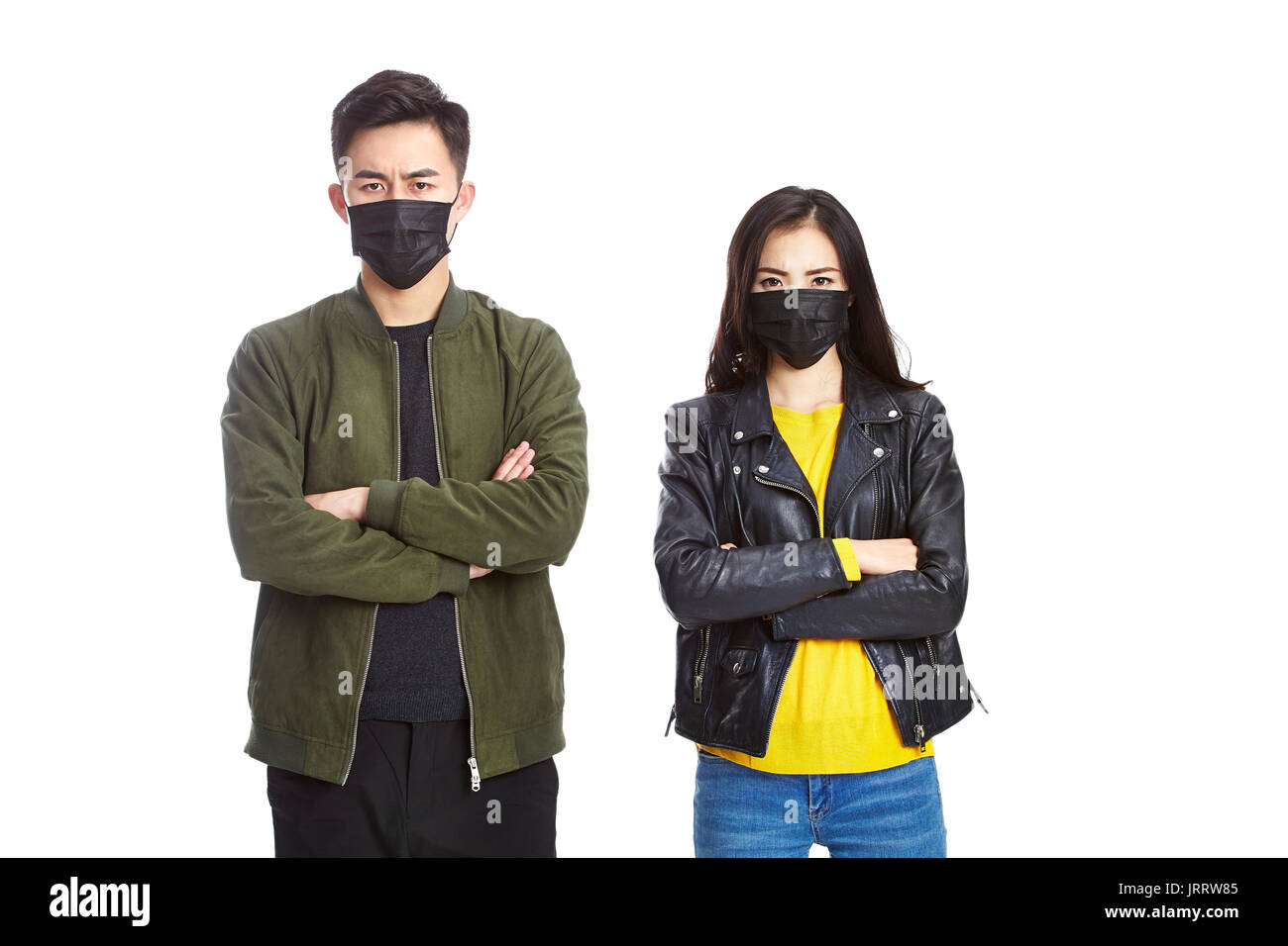 young asian man and woman wearing black mask looking at camera frowning, isolated on white background. Stock Photo