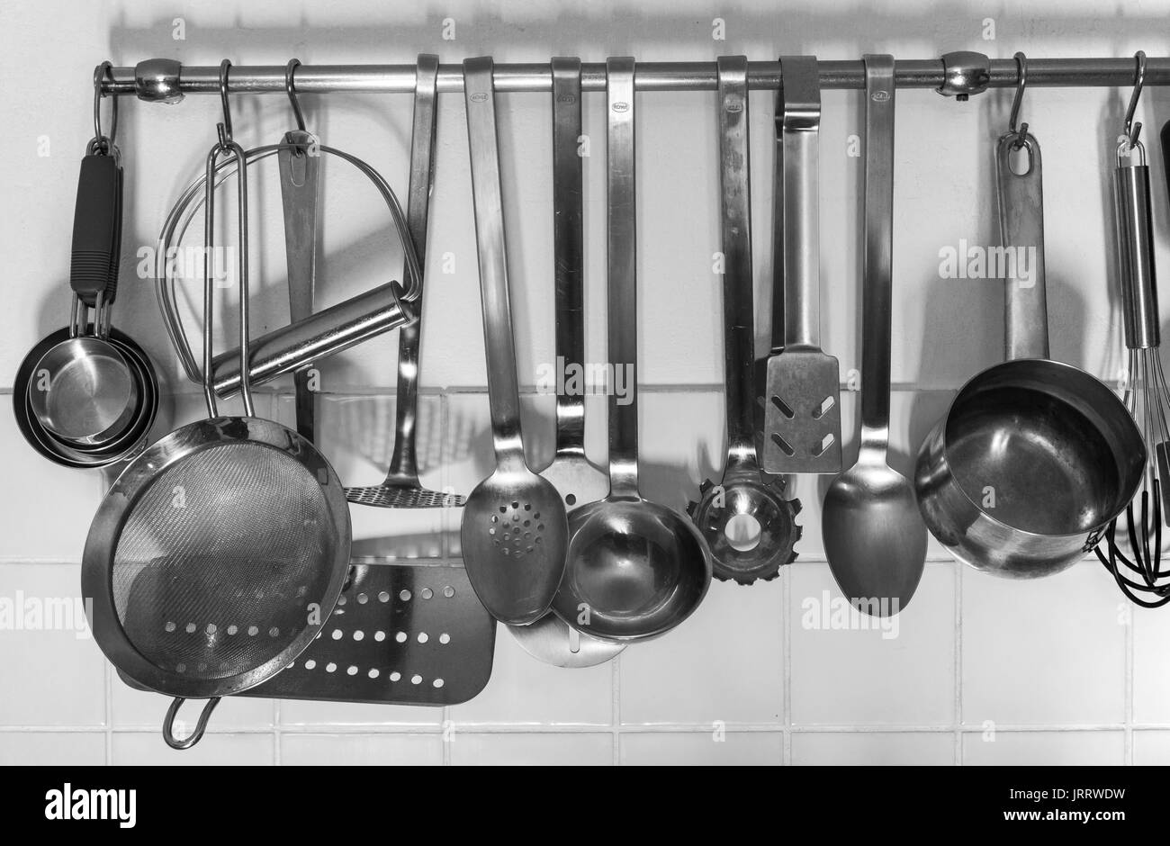Various kitchen utensils hanging from a rack Stock Photo