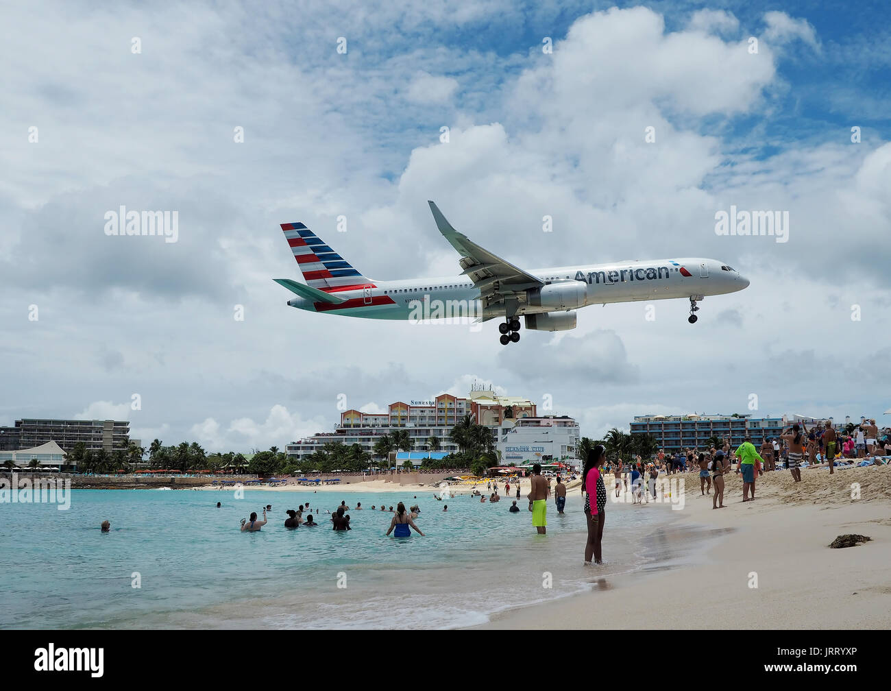 An American Airlines Boeing 757-200 lands at Princess Juliana International Airport as tourists take photos from Maho Beach in Sint Maarten Stock Photo