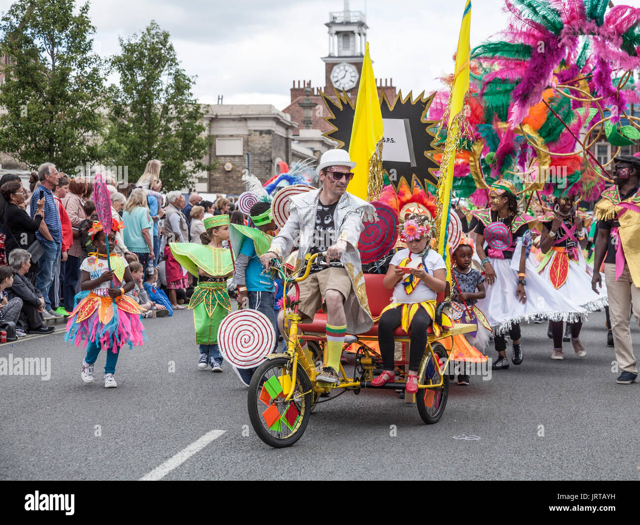 Caption 62/150 People riding tricycles and marching down the High