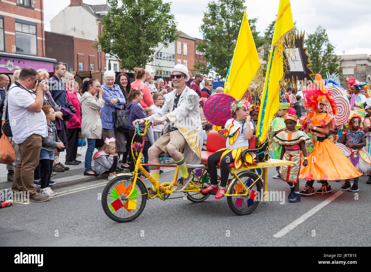 Caption 62/150 People riding tricycles and marching down the High