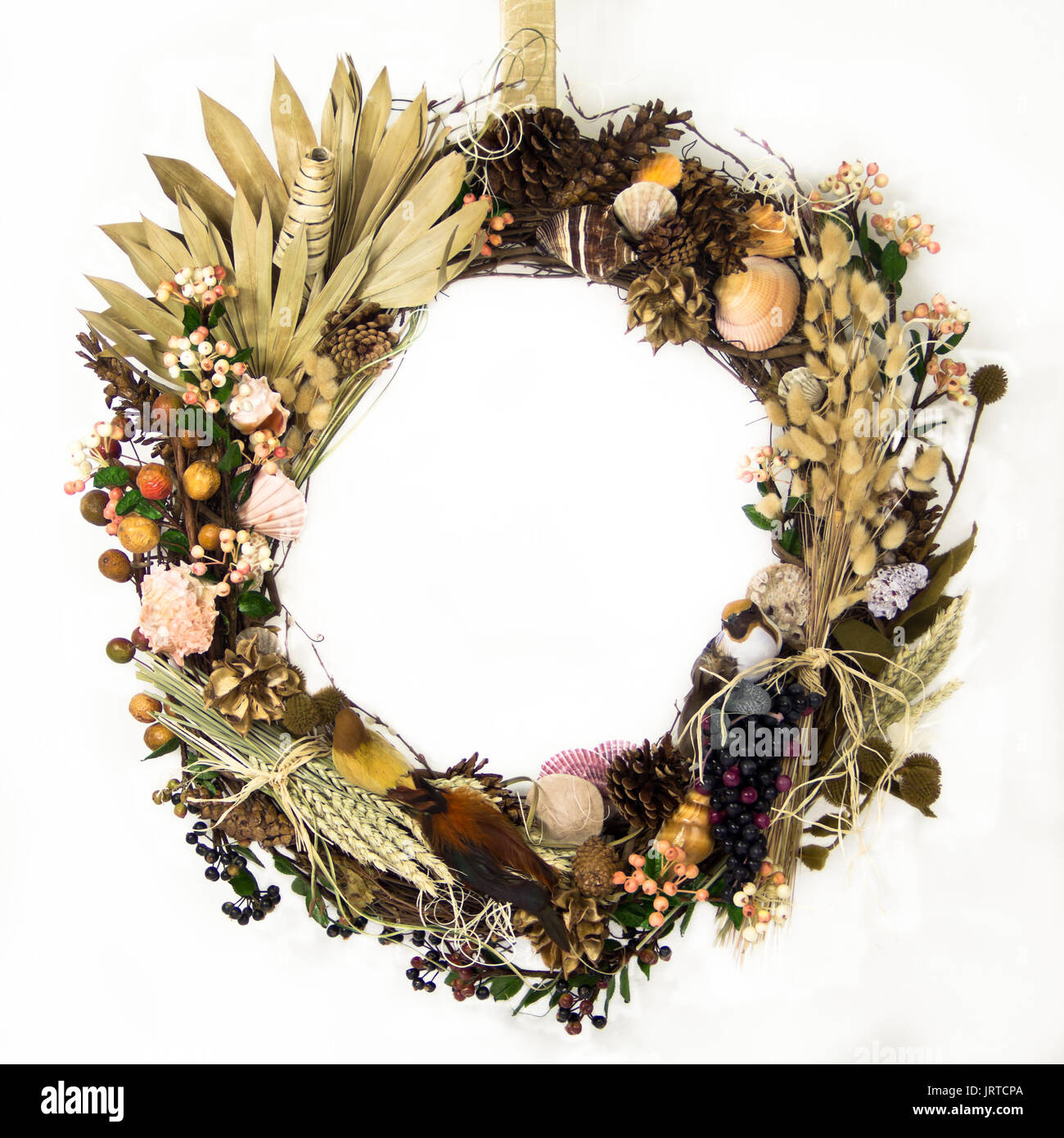 A natural twig wreath is decorated with grasses, grains, fronds, raffia ...