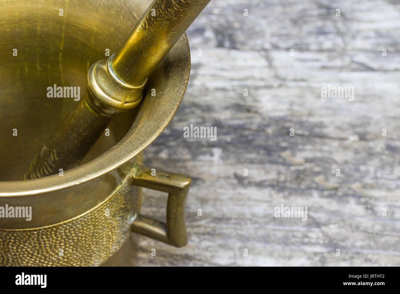 Closeup view of the vintage mortar brass standing on the old wooden desk. Free place for your text is on the right side of the photo. Stock Photo