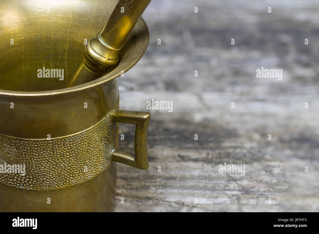 Closeup side view of the mortar brass standing on the old wooden desk. Free place for your text is on the right side of the photo. Stock Photo
