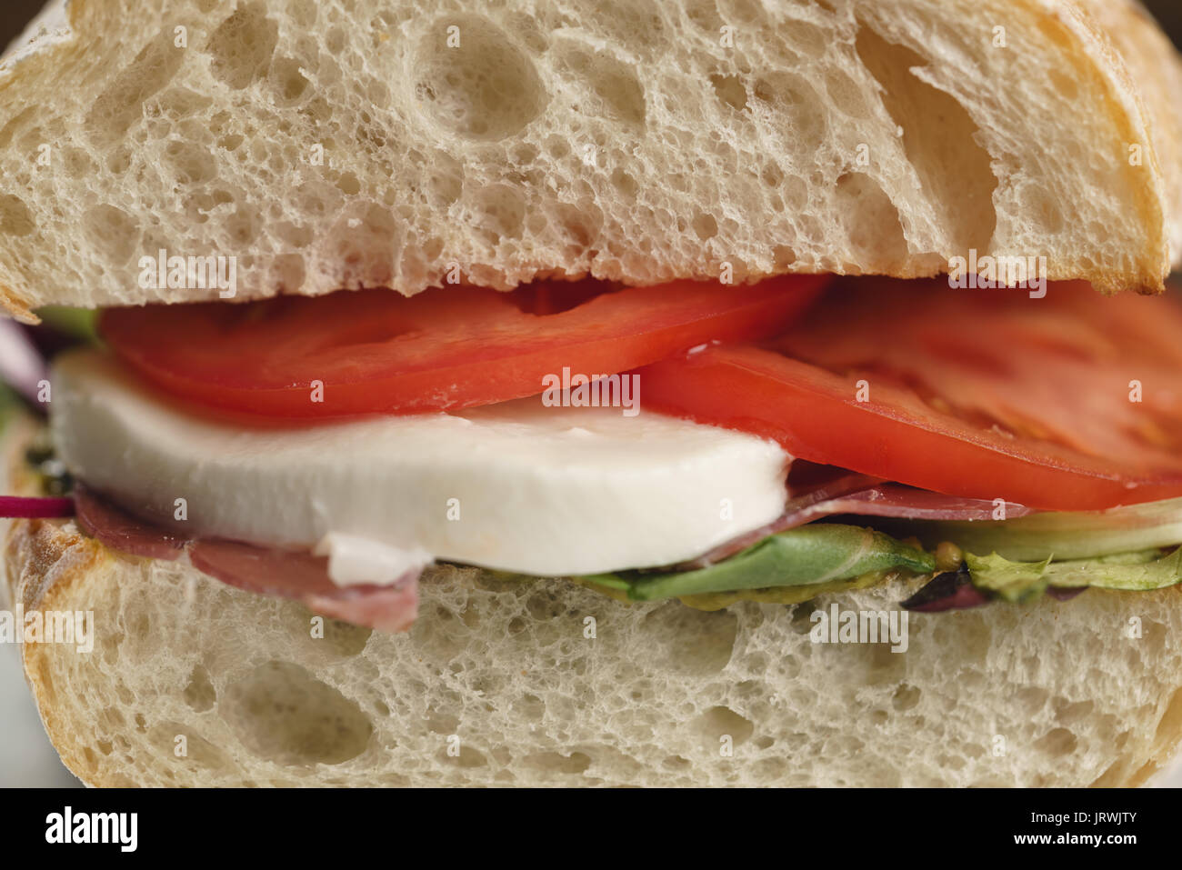 closeup shot of ciabatta sandwich with speck, mozzarella and vegetables Stock Photo