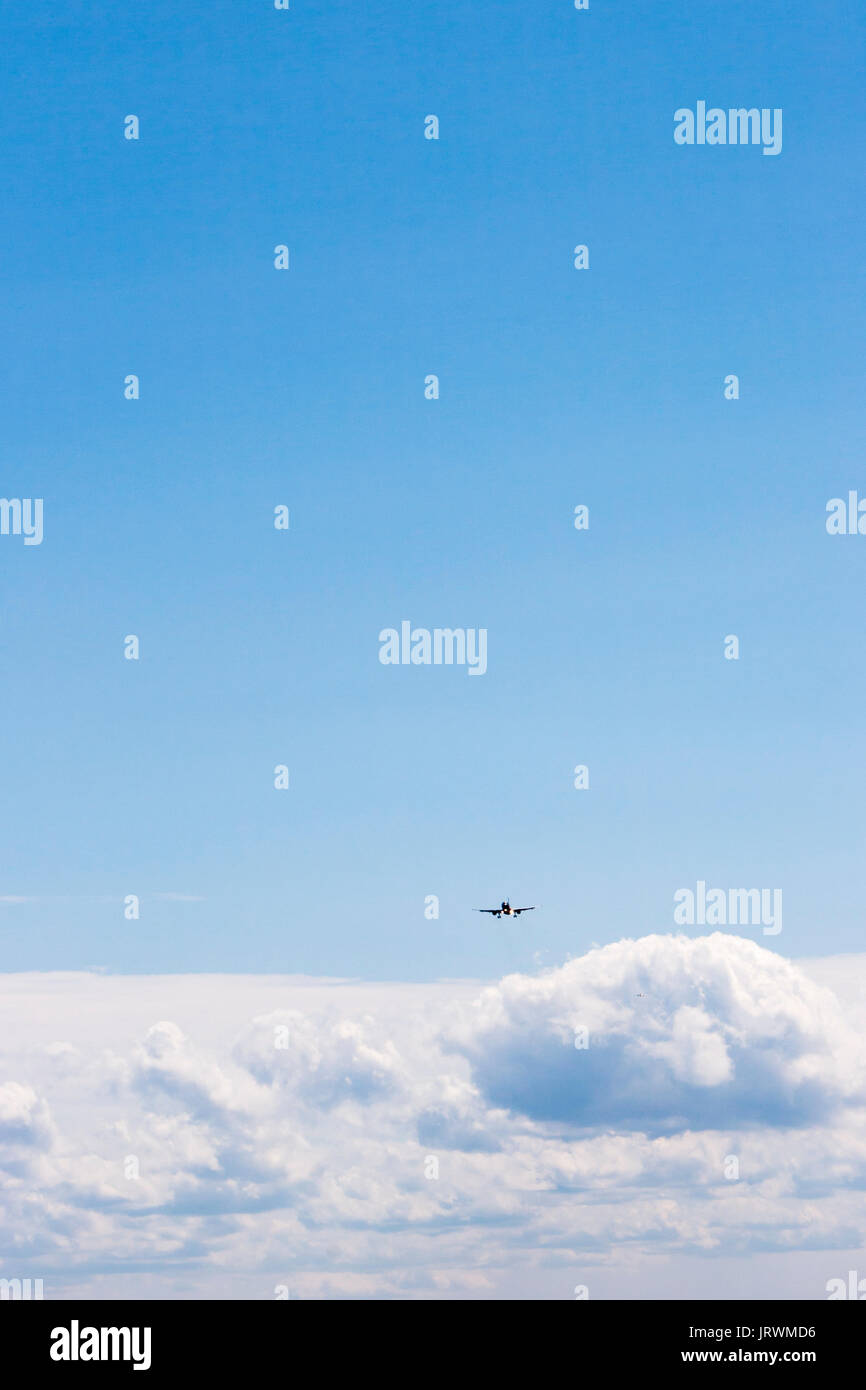 Airplane flying across a blue sky above white clouds Stock Photo - Alamy