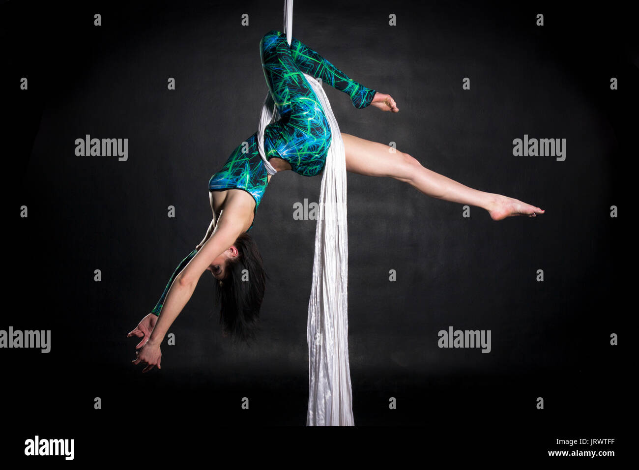 Aerialist woman doing some flexibility and strength tricks on silks Stock Photo