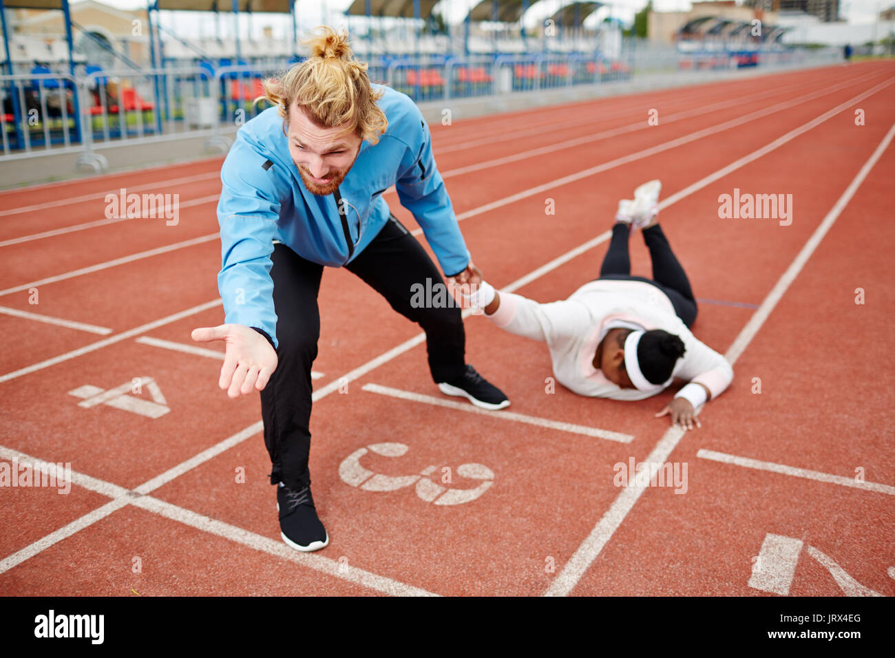 Sport coach dragging exhausted plump client towards finishing line Stock Photo