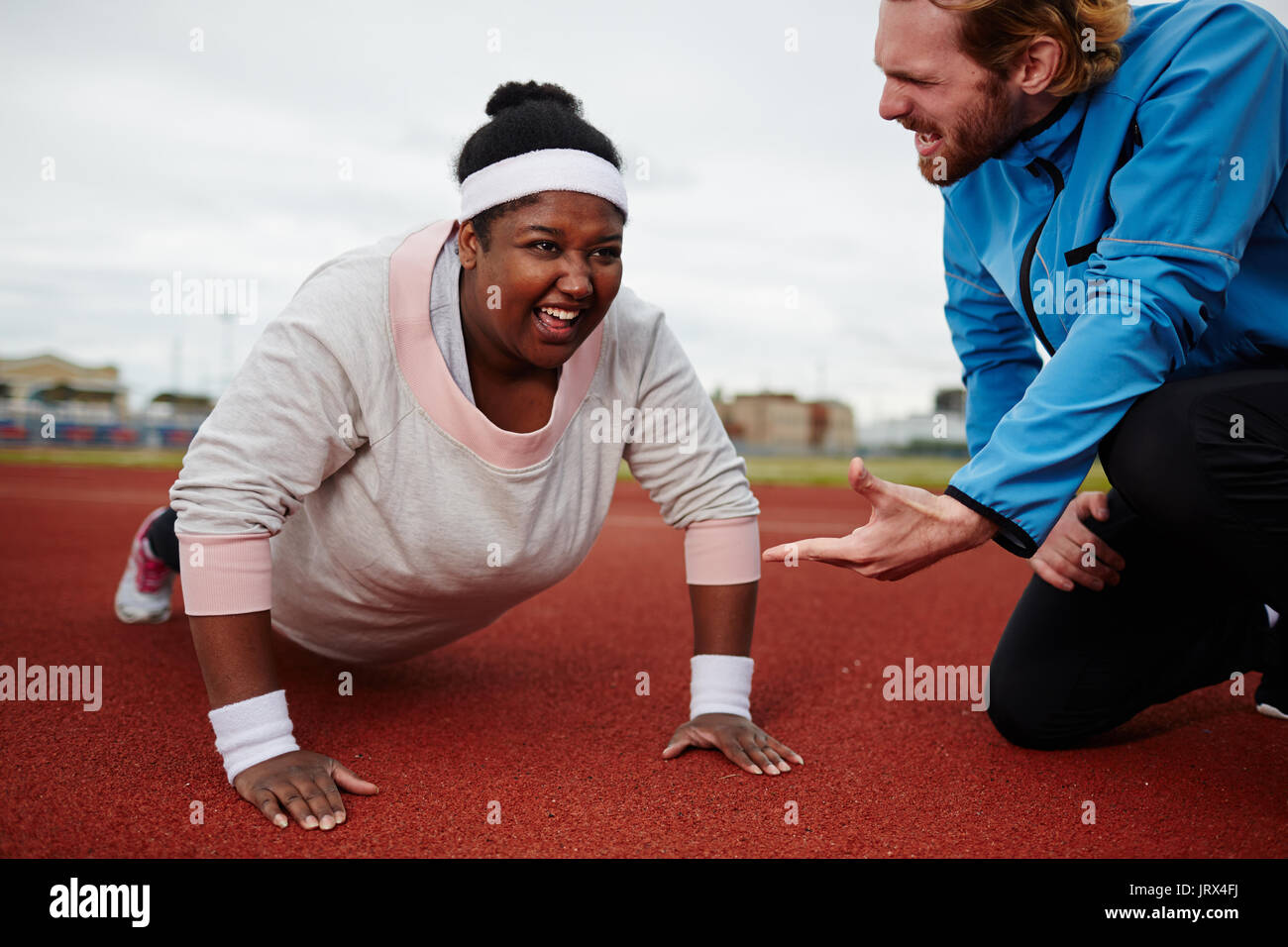 Fat woman doing push ups motivated by personal coach Stock Photo
