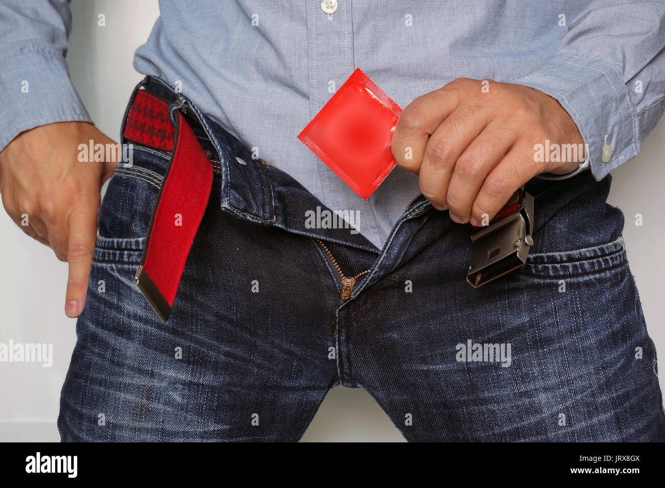 Cropped image of a man holding condom in hand while taking it from jeans. Stock Photo
