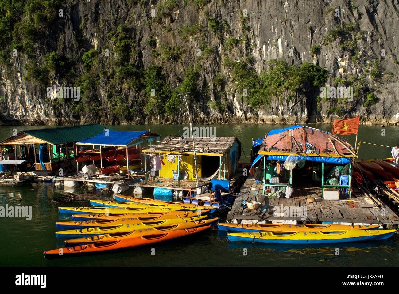 Kayaking past a floating fishing village in Halong Bay. Fish farm village amongst karst limestone mountains at Cat Ba National Park, Ha long,Halong Ba Stock Photo