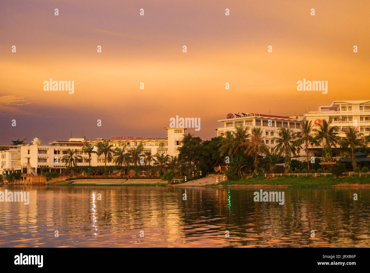 River front hotels. Dragon boat cuises at sunset on the river Huong (Perfume River). Vietnam. Dragon head and excursion boat, Song Huong or Huong Gian Stock Photo