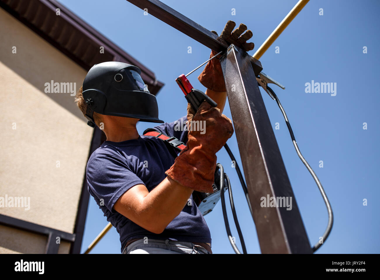 Man welding metal construction at his backyard. Stock Photo