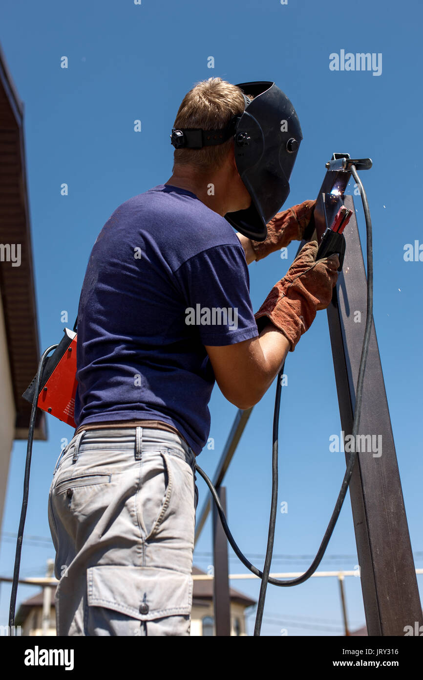 Man welding metal construction at his backyard. Stock Photo