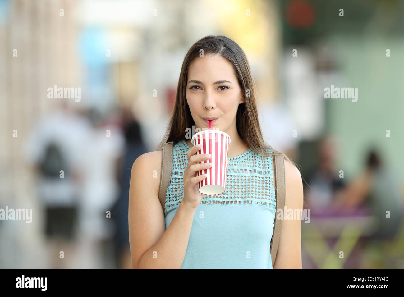 Front view of a girl sipping a takeaway drink walking on the street Stock Photo