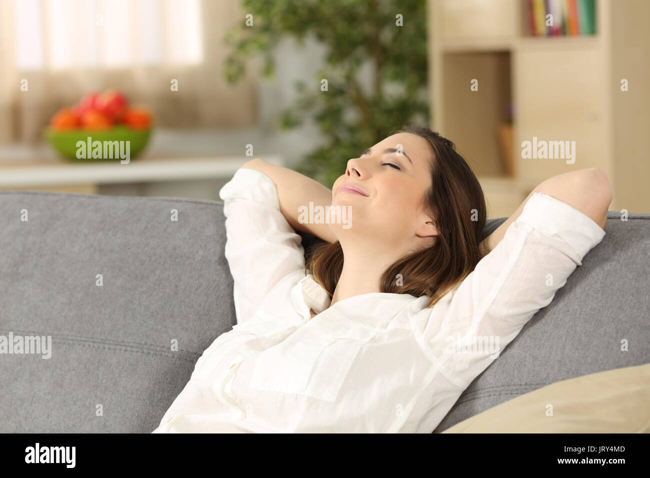 Happy homeowner relaxing alone sitting on a couch at home Stock Photo