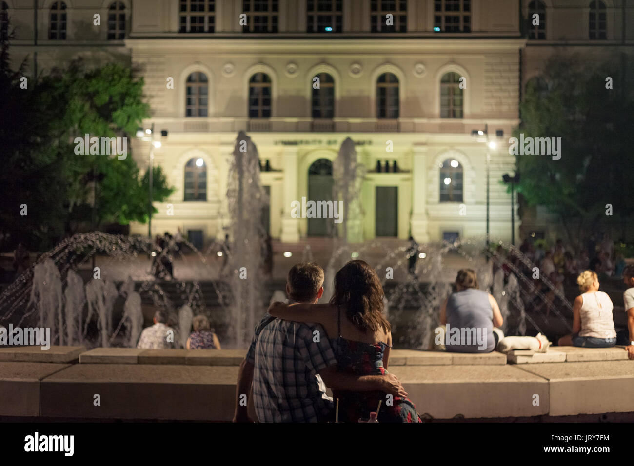 SZEGED, HUNGARY - JULY 22, 2017: Lovers in front of the Fountain on Dugonics Ter Square at night in summer. This square, and the university building o Stock Photo