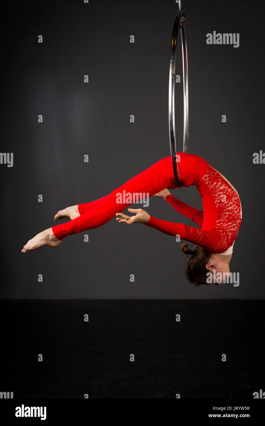 Attractive aerialist woman exercising on aerial ring (lyra) Stock Photo