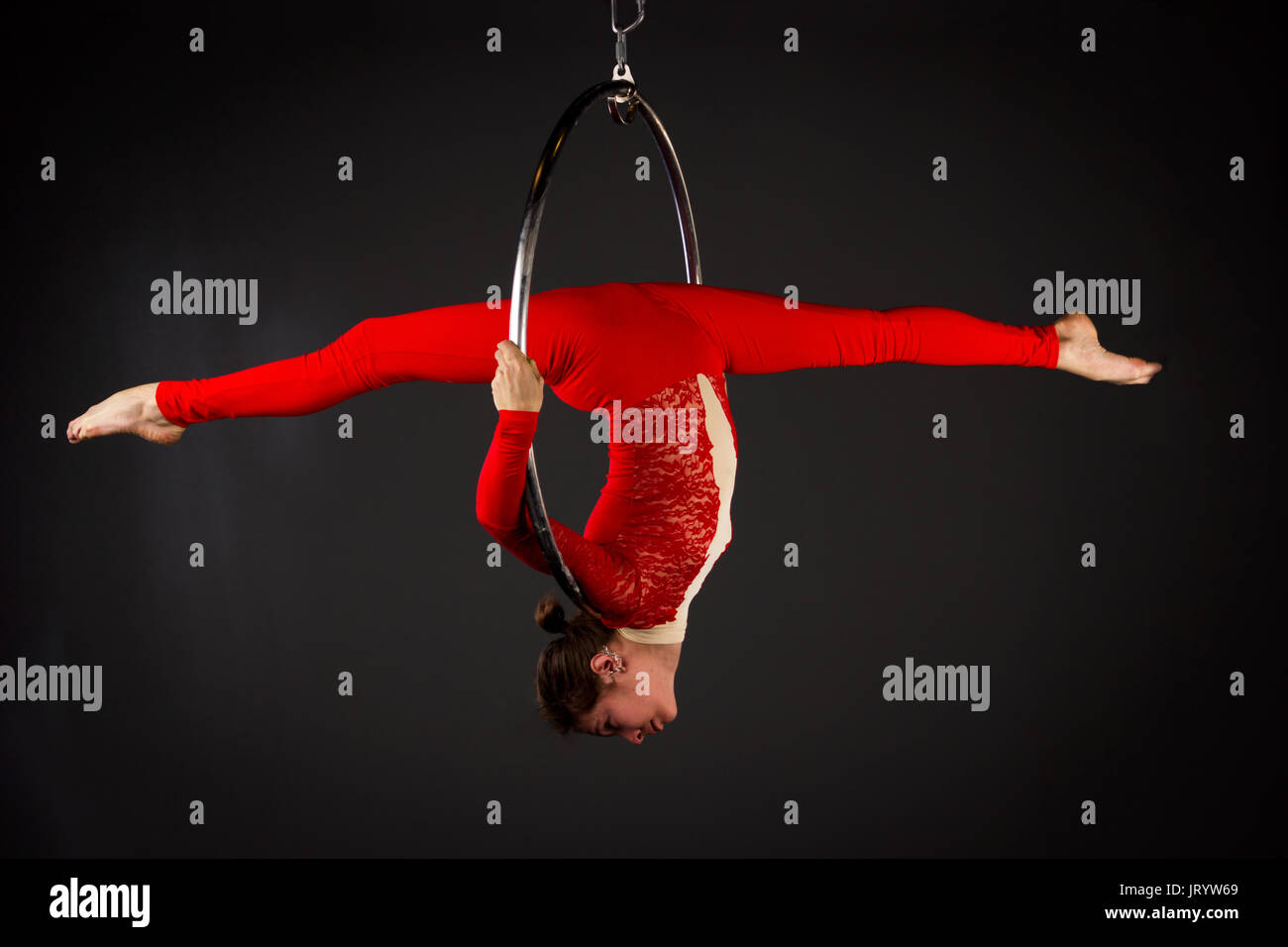 Attractive aerialist woman exercising on aerial ring (lyra) Stock Photo
