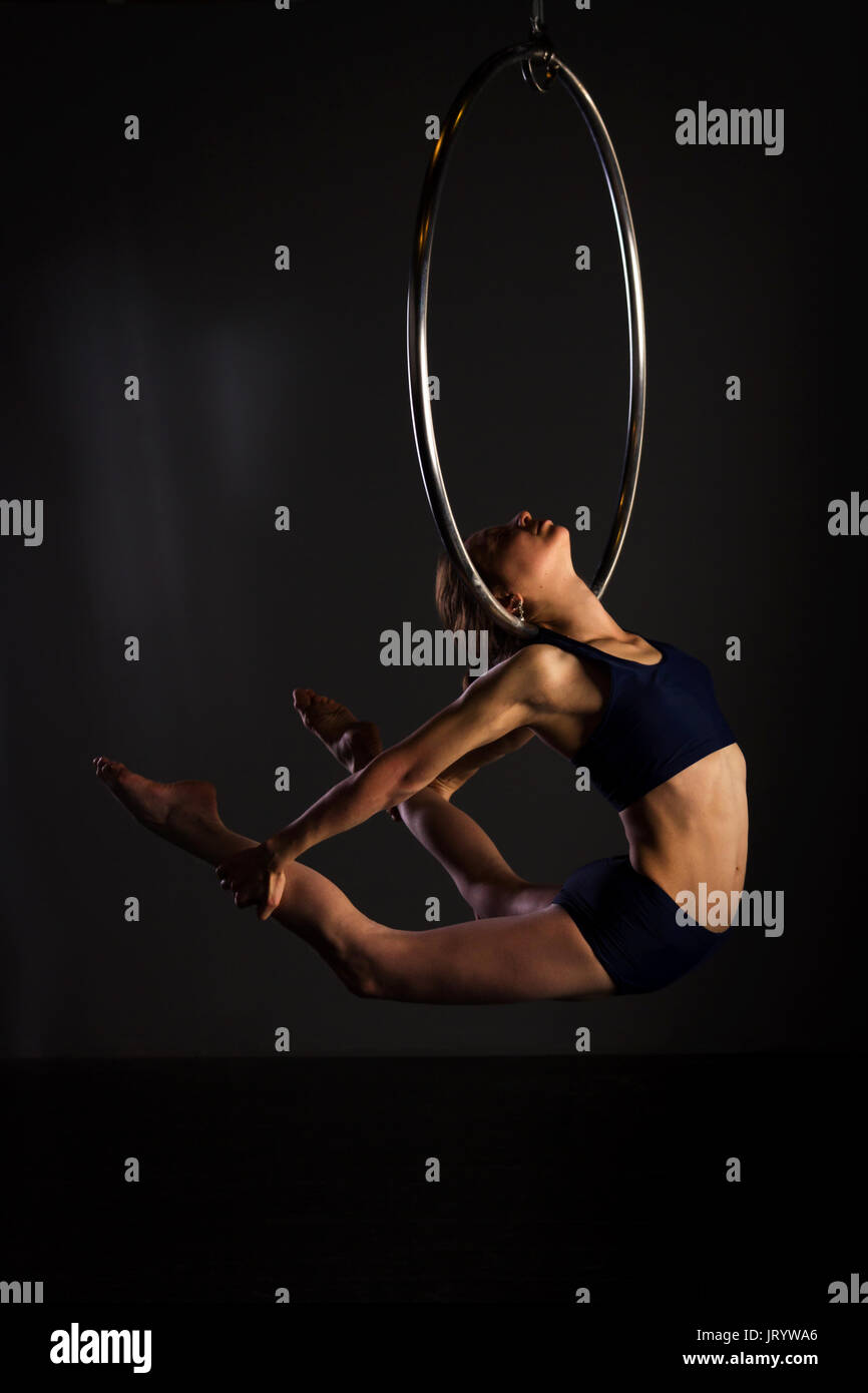 Attractive aerialist woman exercising on aerial ring (lyra Stock Photo