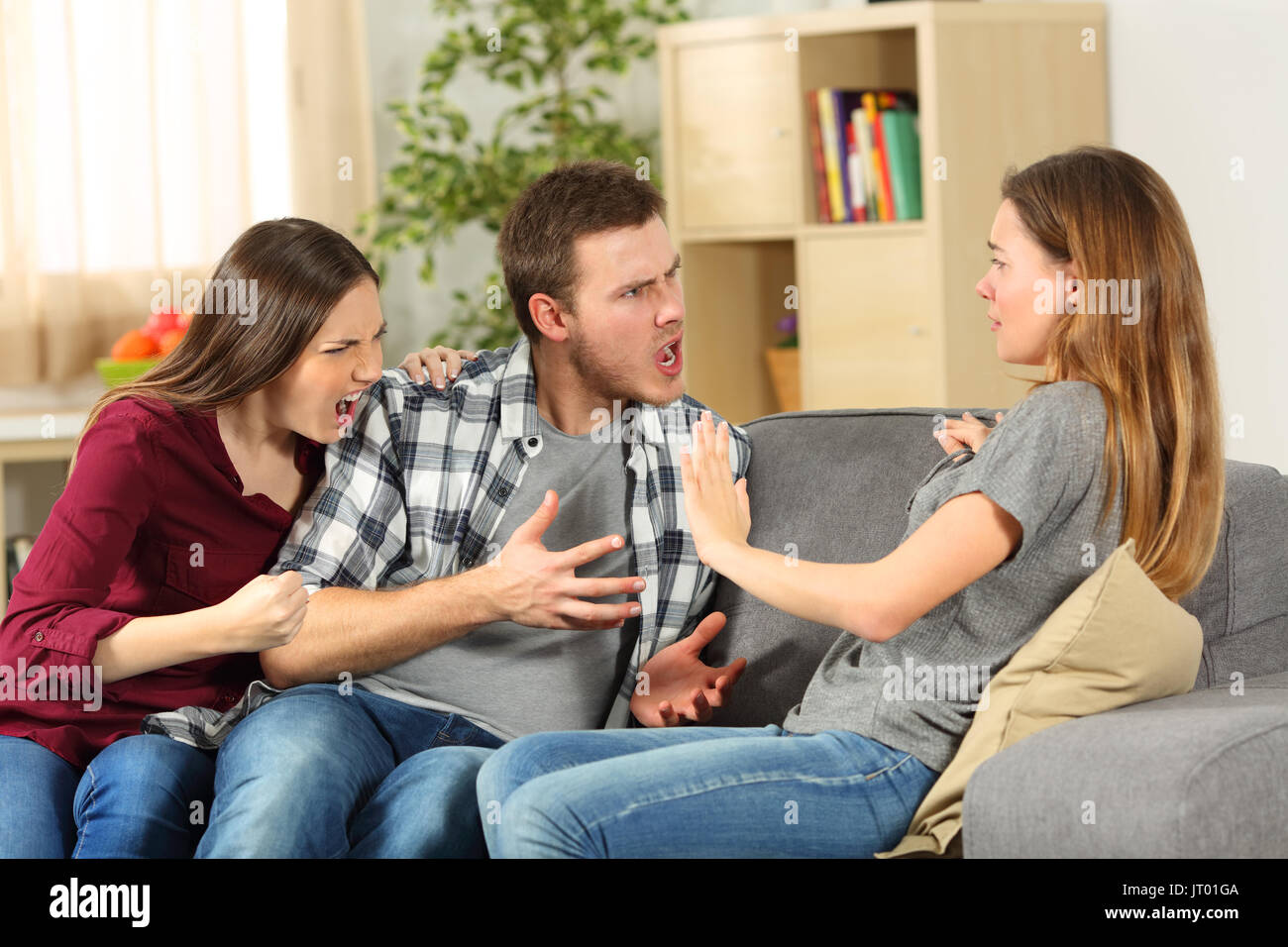 Roommates arguing and shouting each other on a sofa at home Stock Photo