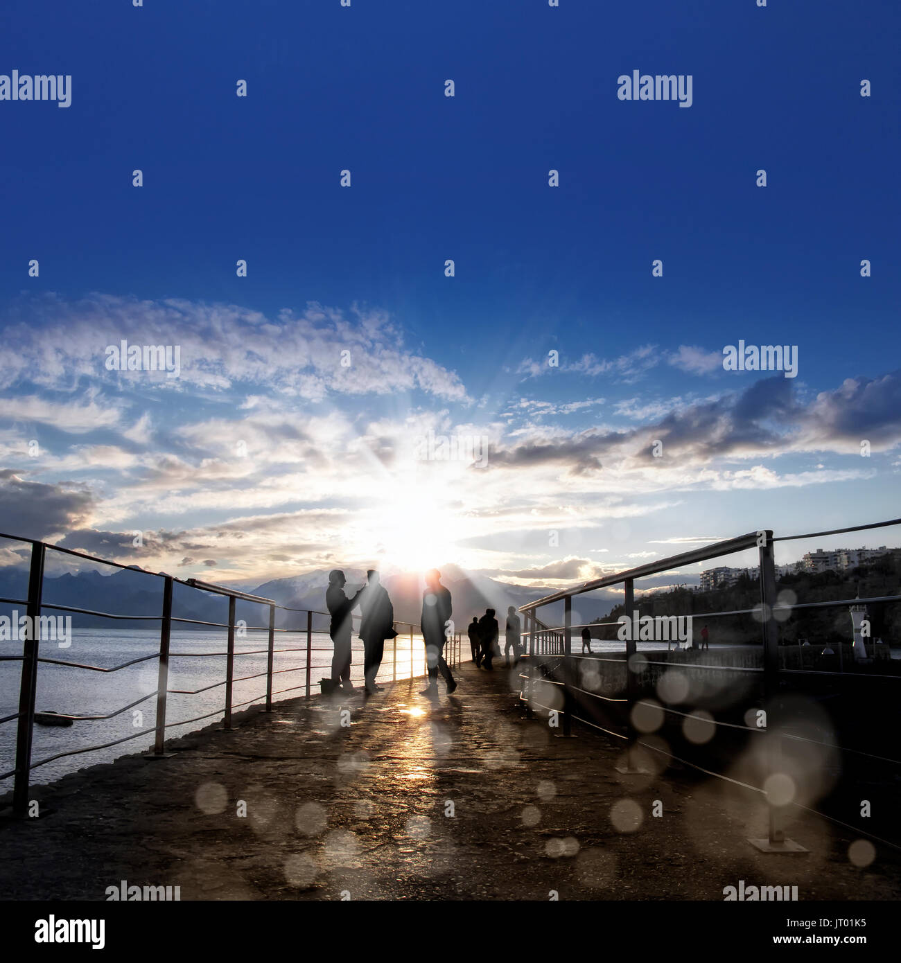 silhouetted people walking on street over sunset sky with sunbeam Stock ...