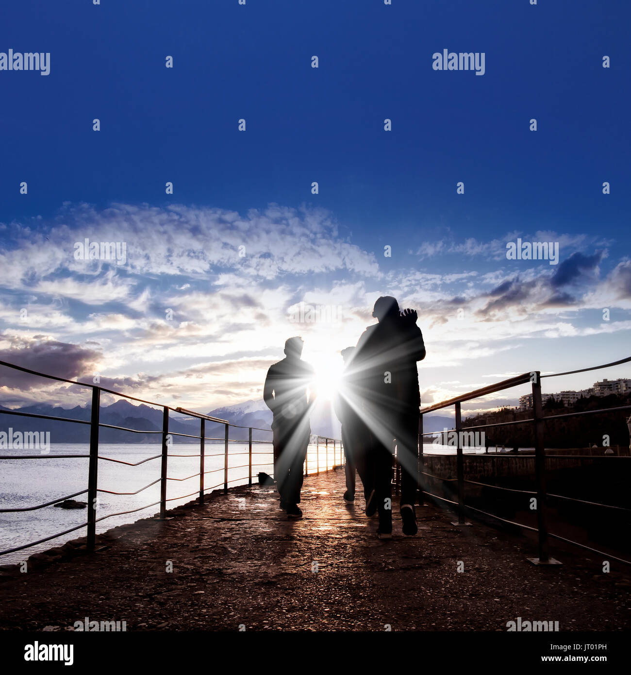 silhouetted people walking on street over sunset sky with sunbeam Stock ...