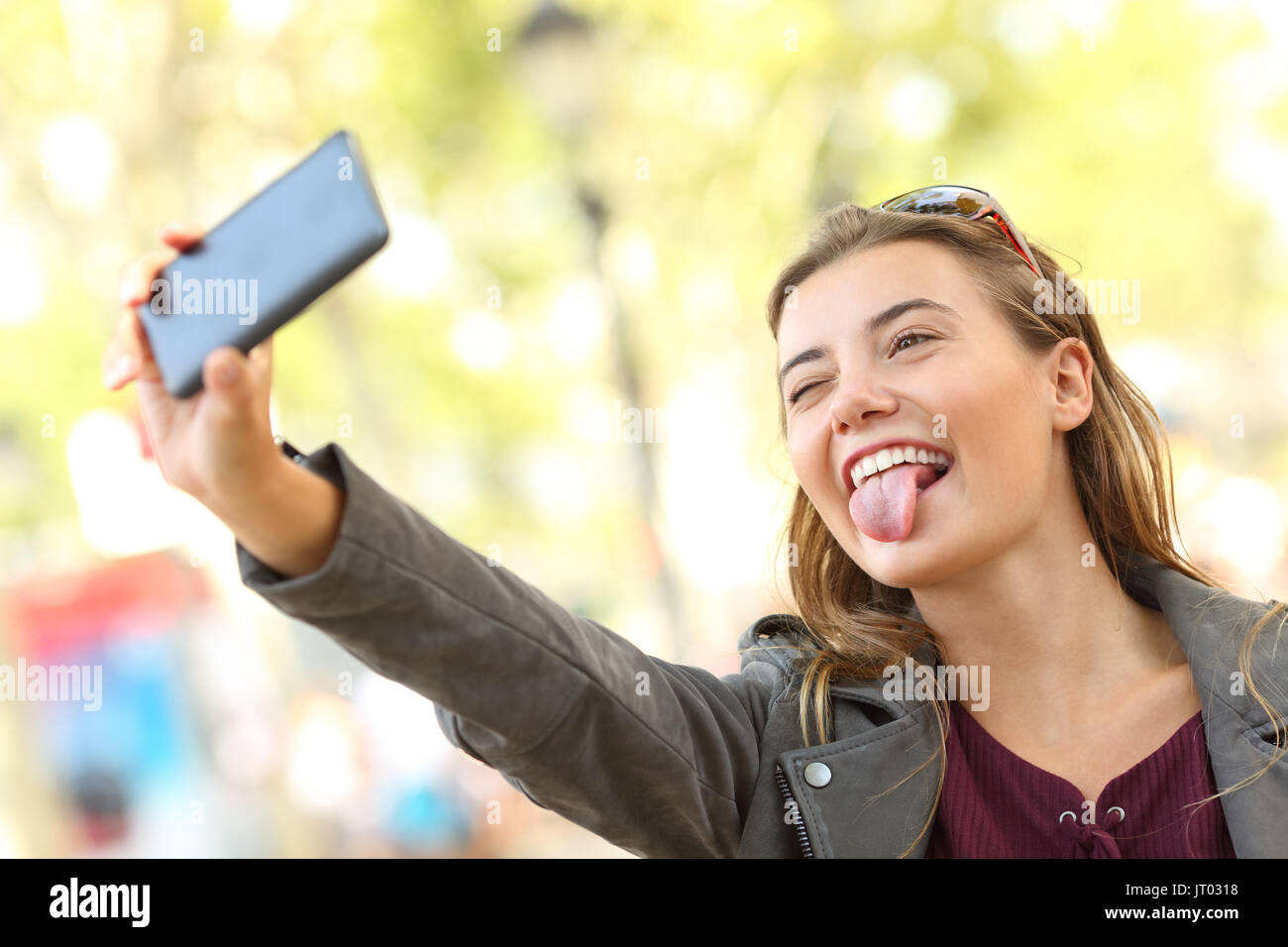 Portrait of a funny teen taking selfies and grimacing on the street Stock Photo