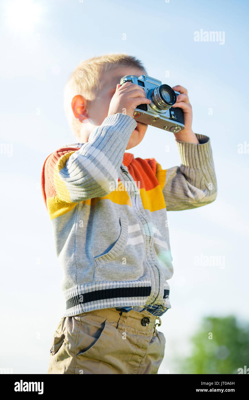 Little boy with an old camera shooting outdoor. Stock Photo