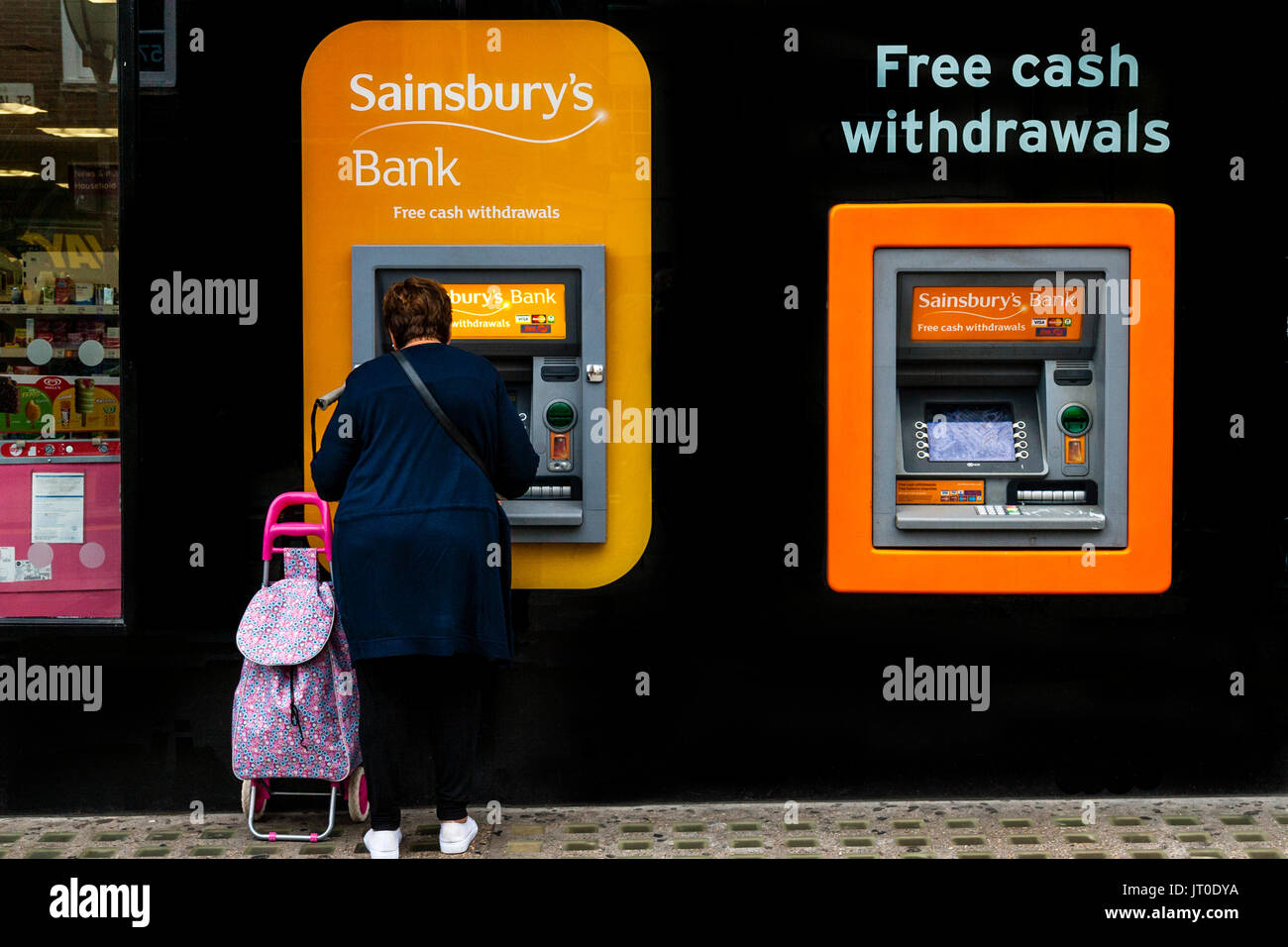 A Woman Withdraws Cash From An ATM, Brighton, Sussex, UK Stock Photo