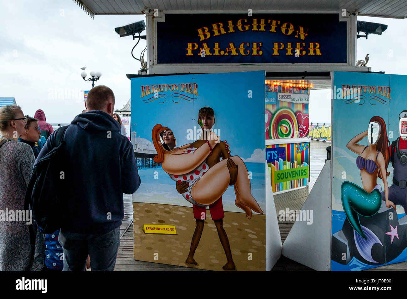 People Pose For Pictures Looking Out Of A Face Cut Out Board, Brighton Pier, Brighton, Sussex, UK Stock Photo