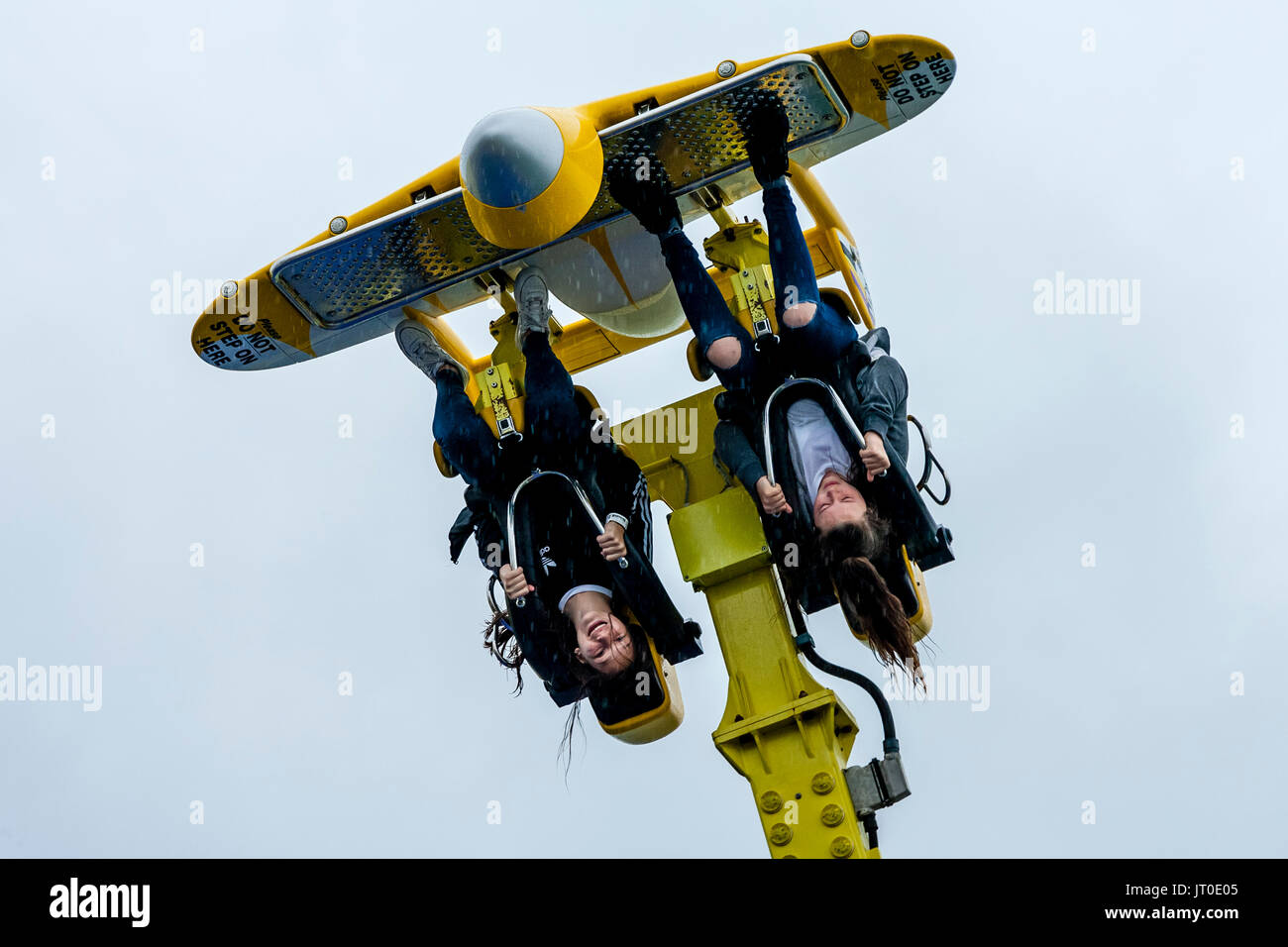 Two Young Women Enjoying A Fairground Ride In The Rain On Brighton Pier, Brighton, East Sussex, UK Stock Photo
