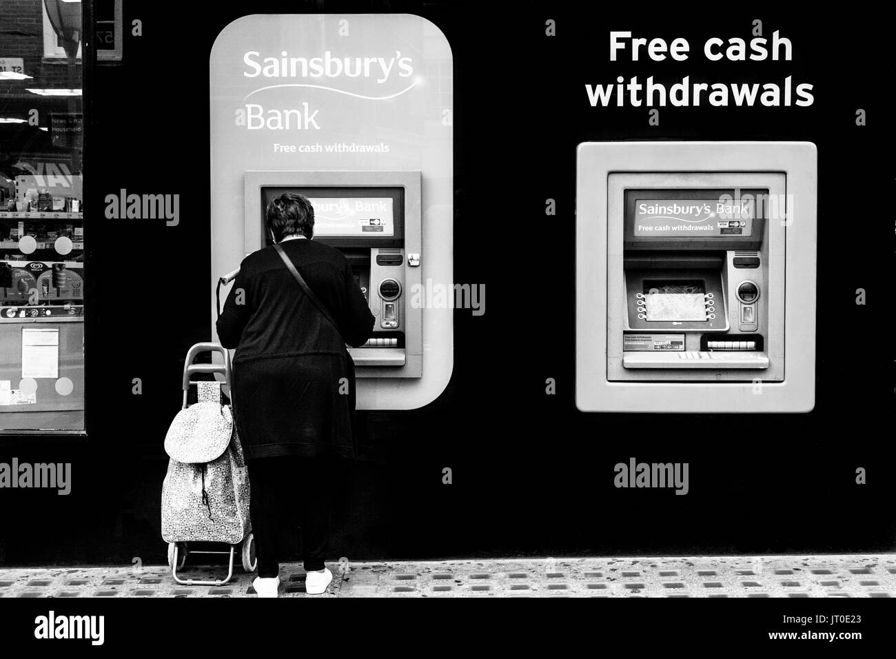 A Woman Withdraws Cash From An ATM, Brighton, Sussex, UK Stock Photo