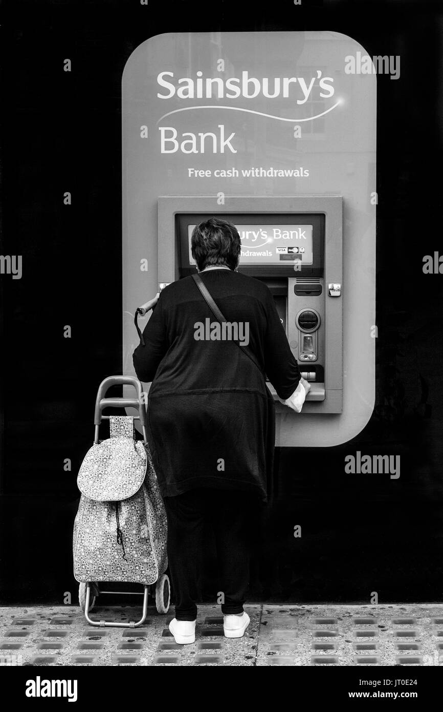 A Woman Withdraws Cash From An ATM, Brighton, Sussex, UK Stock Photo