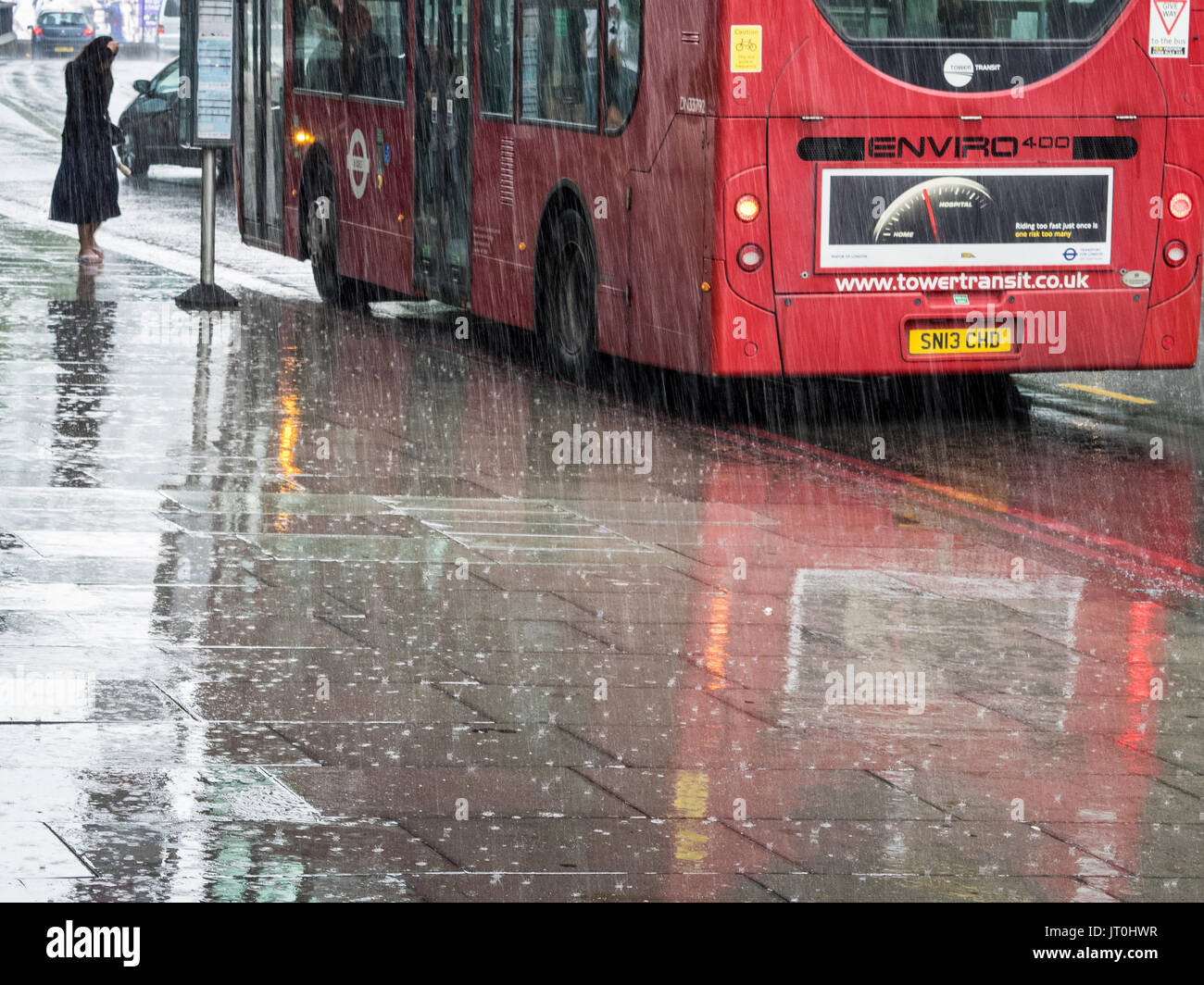 Bus in the Rain - a passenger waits in the pouring rain to board a bus in Central London, UK Stock Photo