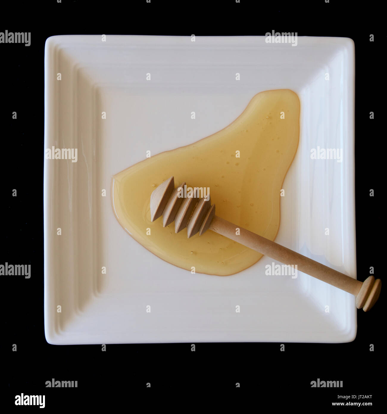 Australian honey on a white plate with a honey dipper. Stock Photo
